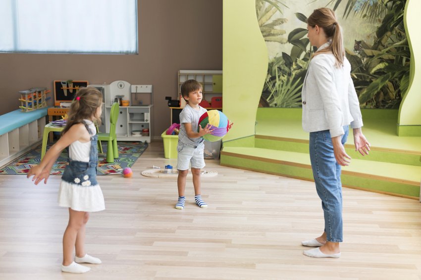 maestra jugando con pelota con niños en actividad física inclusiva